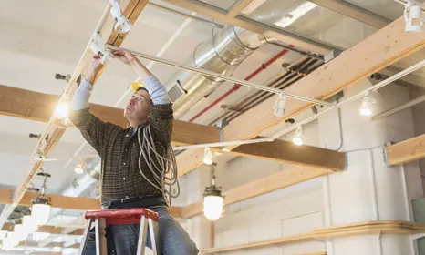 Man fixing broken lights in ceiling